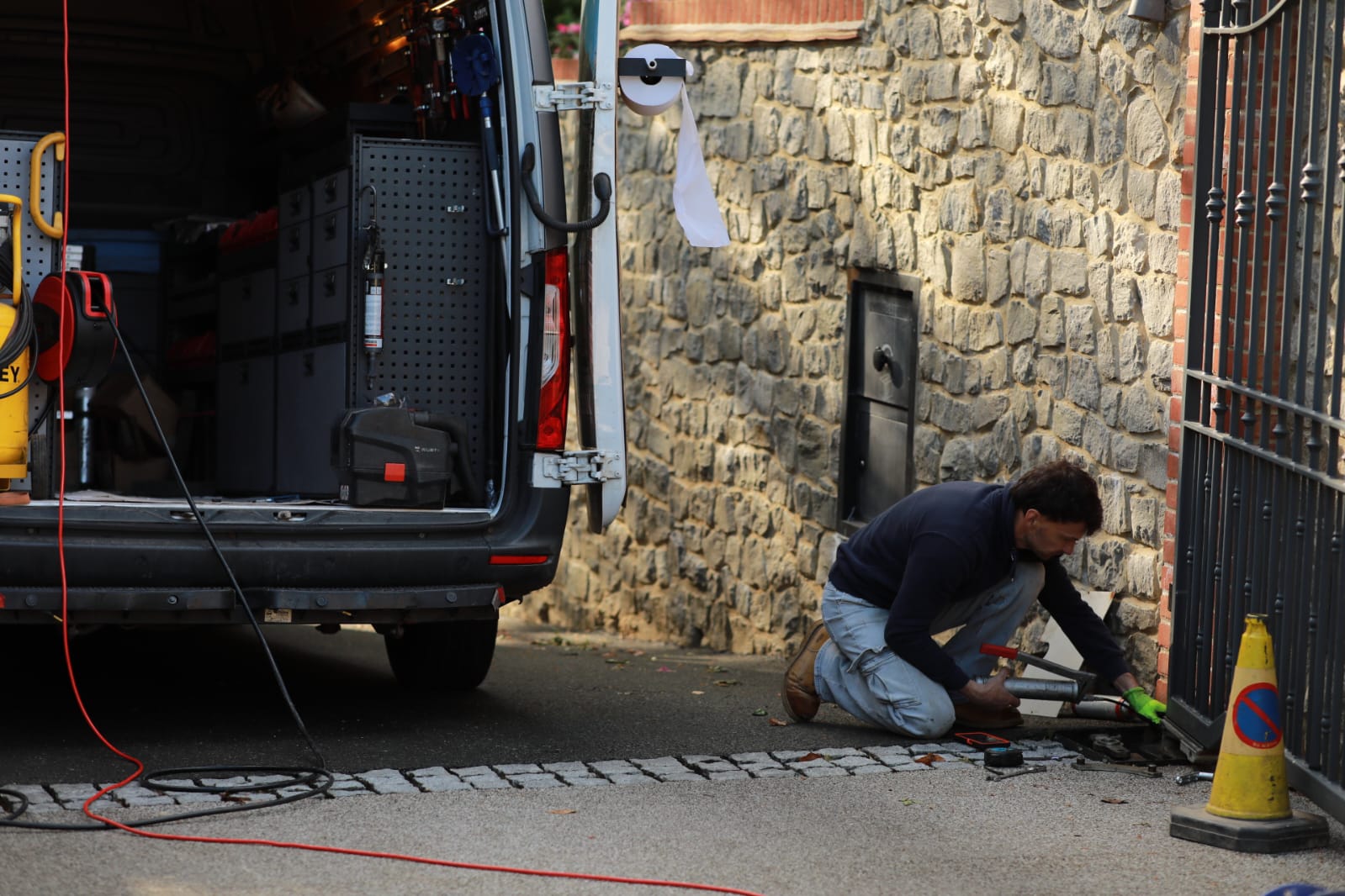 Engineer working onsite on gate cabling next to a stone wall